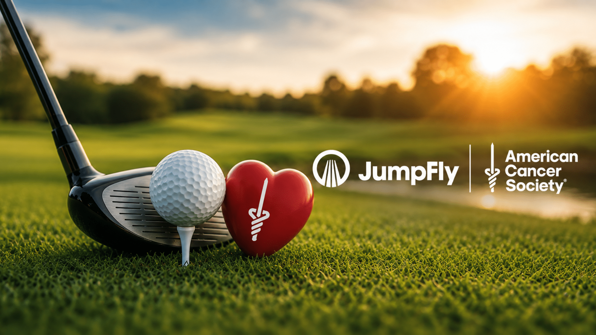 Golf ball on a tee with a club nearby, a red heart-shaped ribbon, and JumpFly + American Cancer Society logos at sunset on a green golf course.